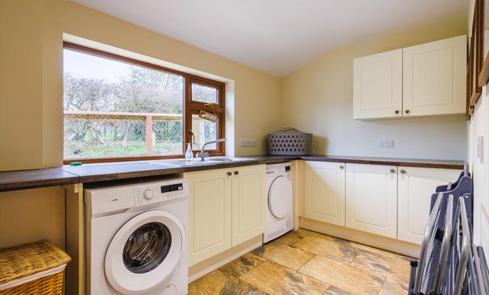 Laundry room with washing machine, tumble dryer, clothes drying racks, washing basket and laundry bin.